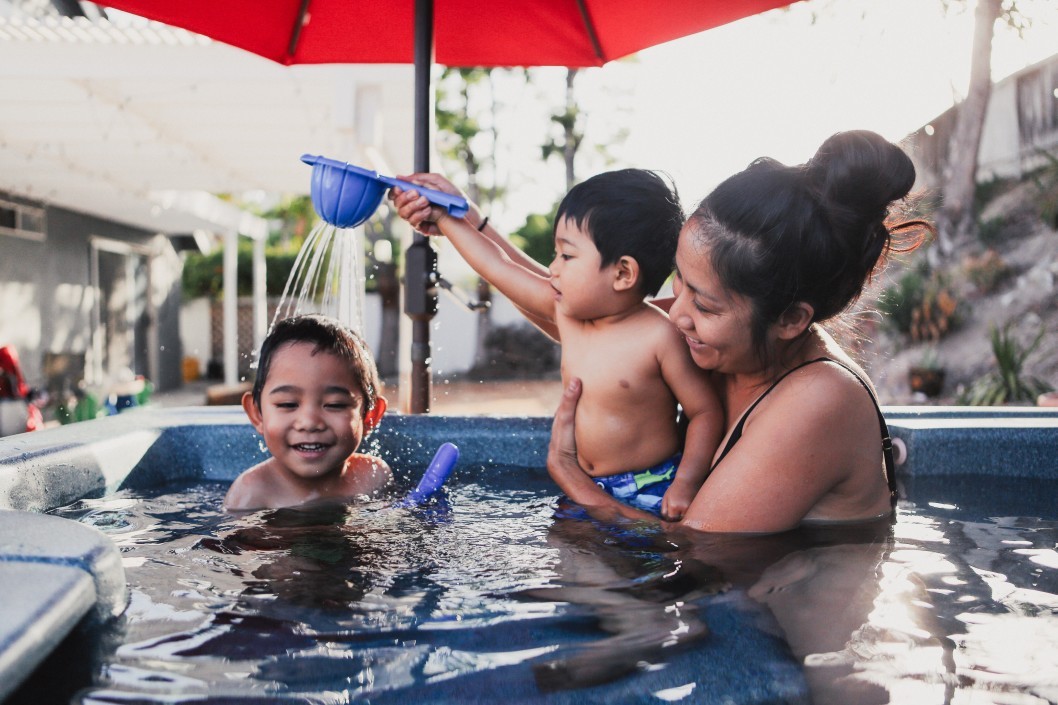 a mother playing with her two kids in the pool
