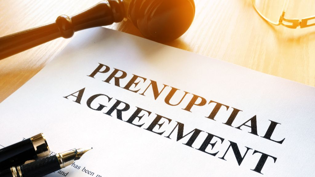 Document titled "Prenuptial Agreement" on a wooden desk with a fountain pen and judge's gavel.