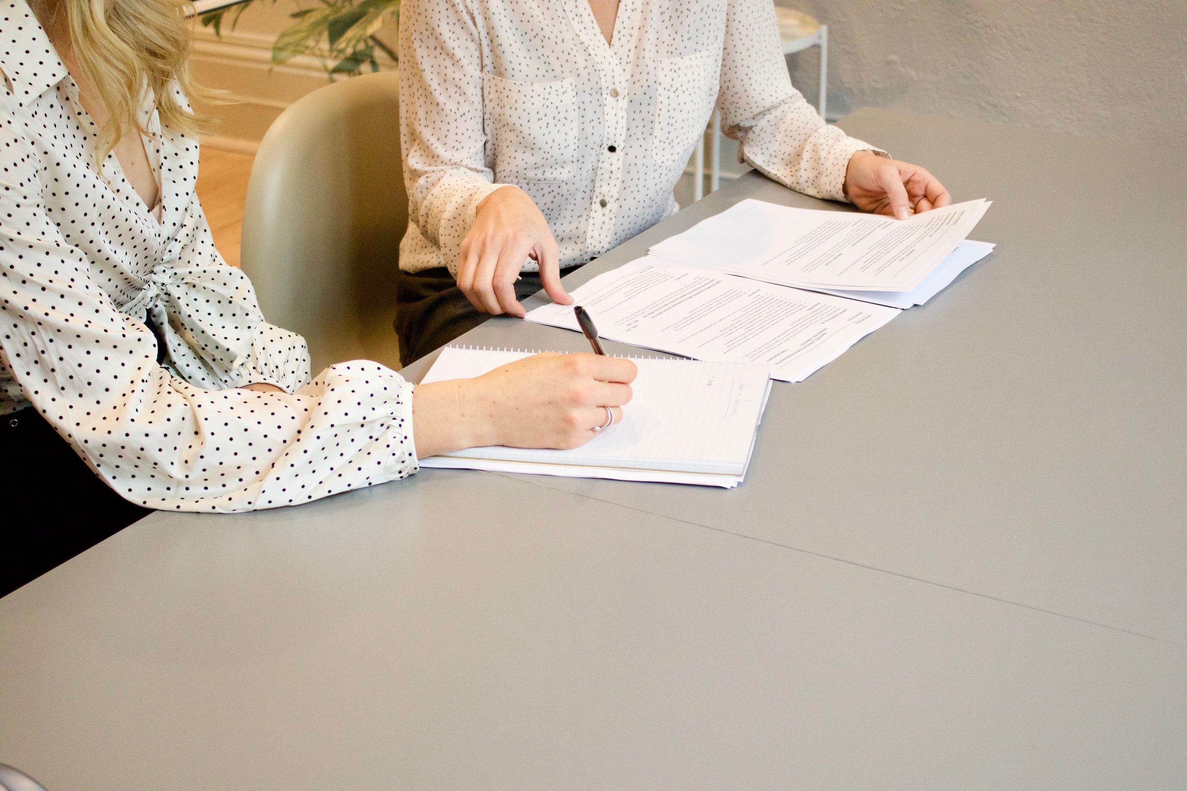 two white women sitting down at table signing papers