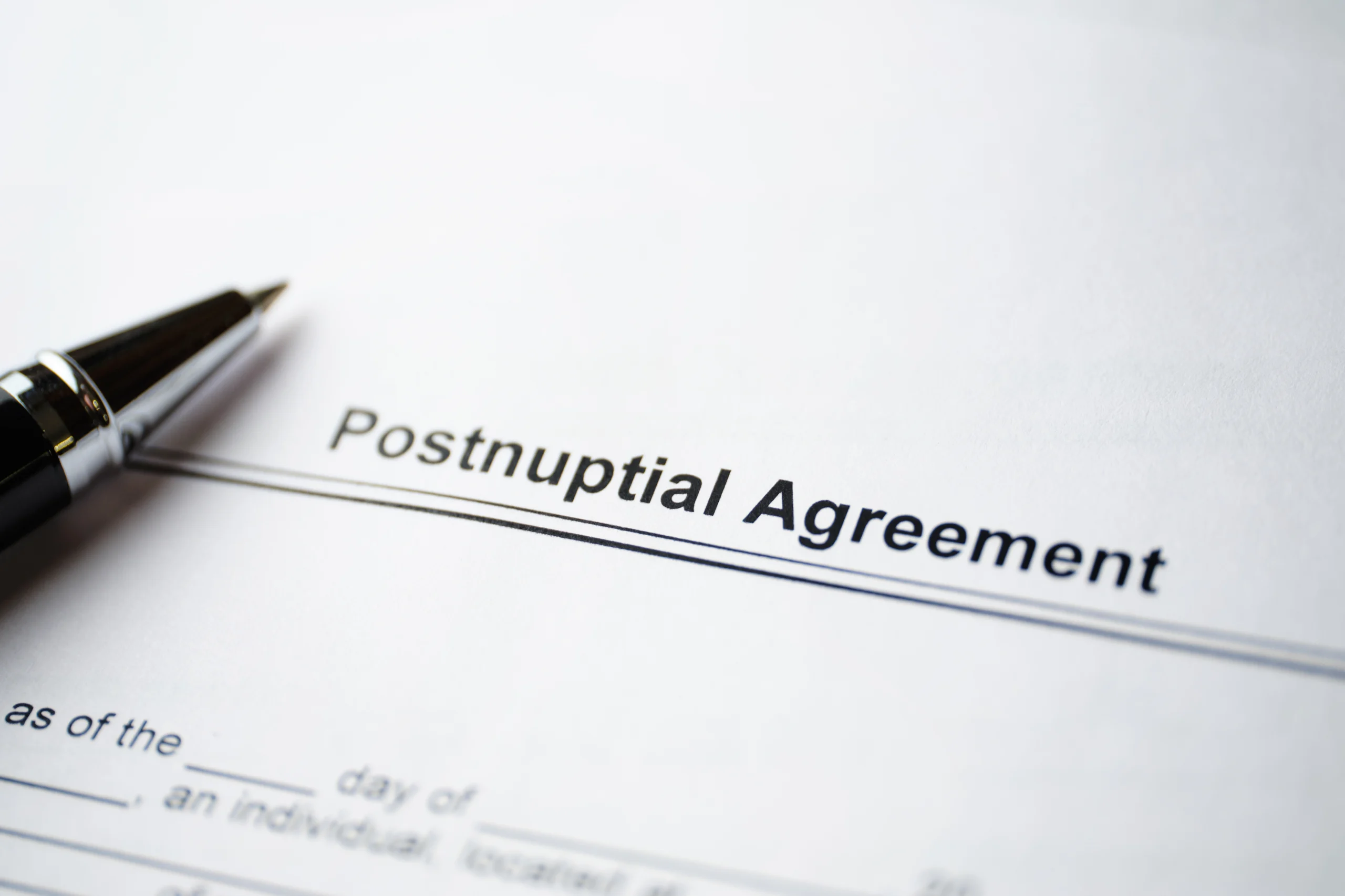 Close-up of a Postnuptial Agreement document with a black pen resting on the paper.