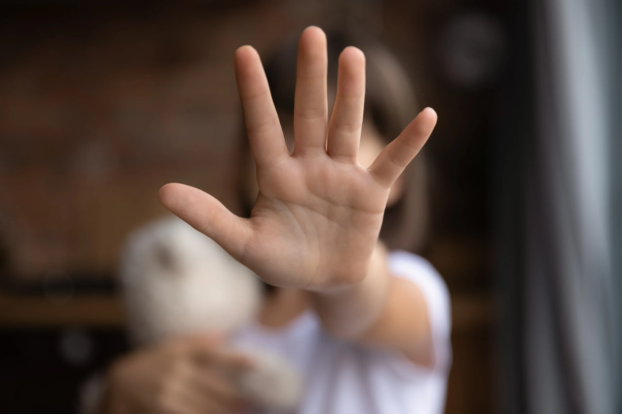 Close-up of an outstretched hand with fingers spread, obscuring the blurred background.