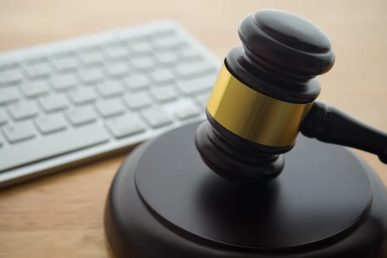 Close-up of a wooden judge's gavel with brass band next to a white computer keyboard.