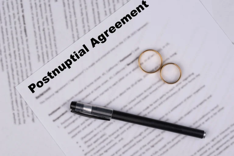 Postnuptial agreement document with two gold wedding rings and a black pen.