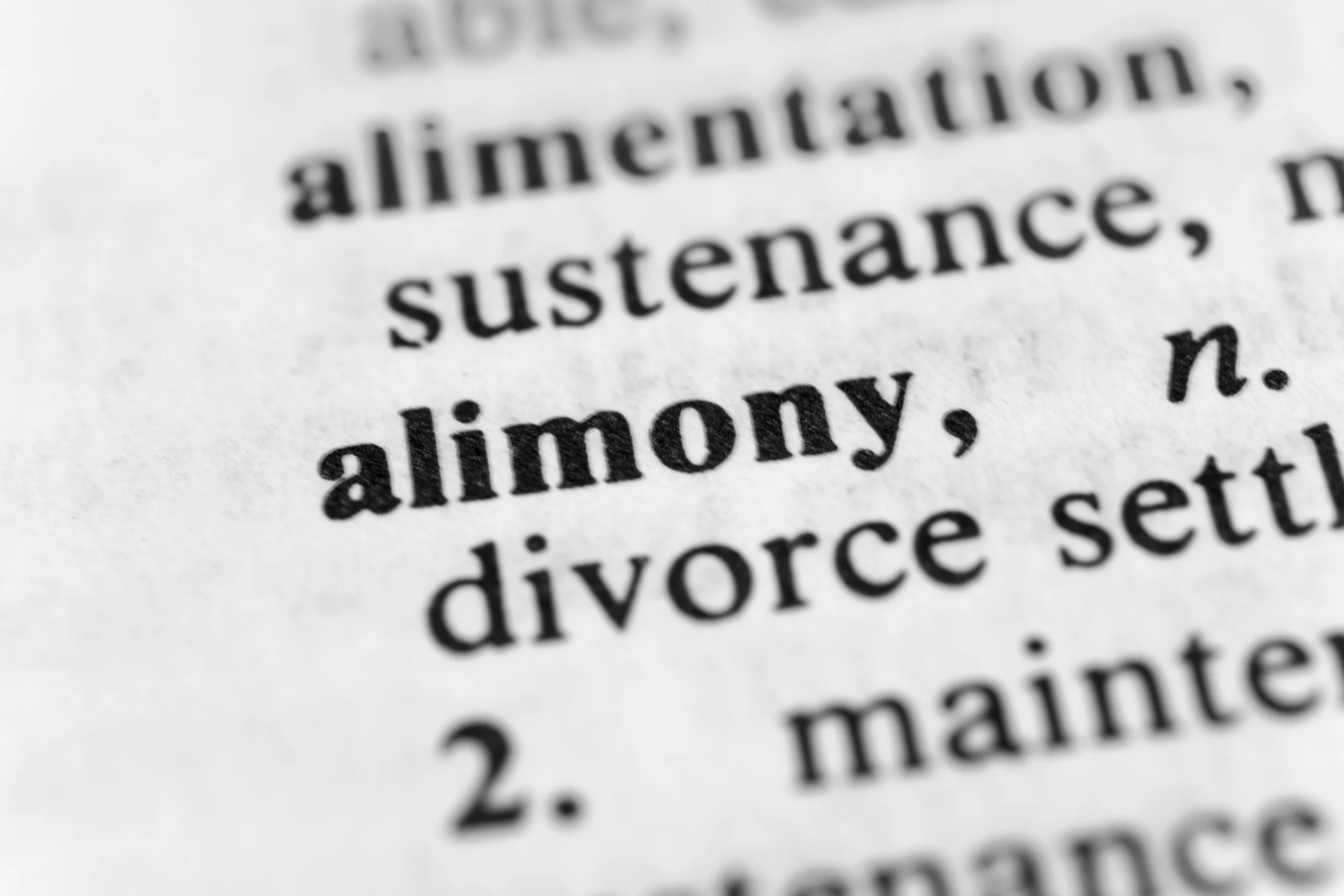 Close-up of a dictionary page highlighting the word "alimony" in bold black text.