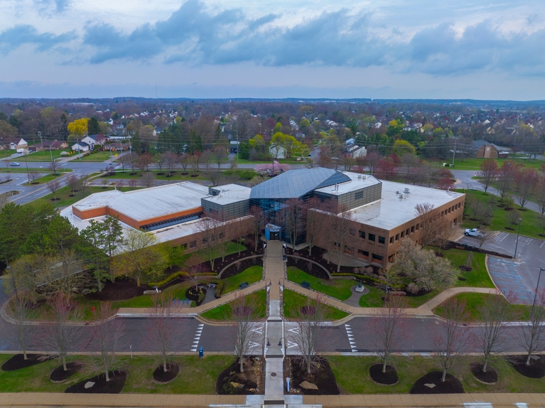 Aerial view of a modern brick office building with surrounding parking lots and landscaped greenery.