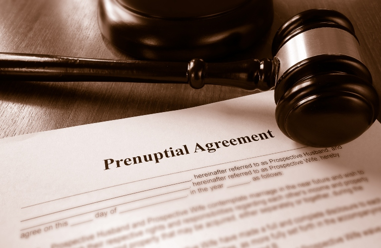 Close-up of a prenuptial agreement document with a wooden judge's gavel on a desk.