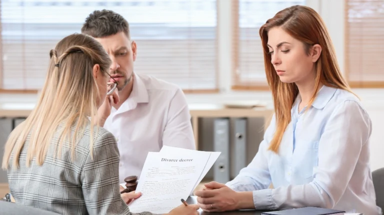 Three adults in a professional office reviewing a divorce decree document.