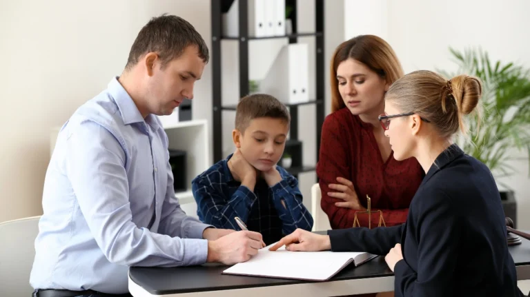 Four people, including a child, engaged in a formal discussion with documents at a table.