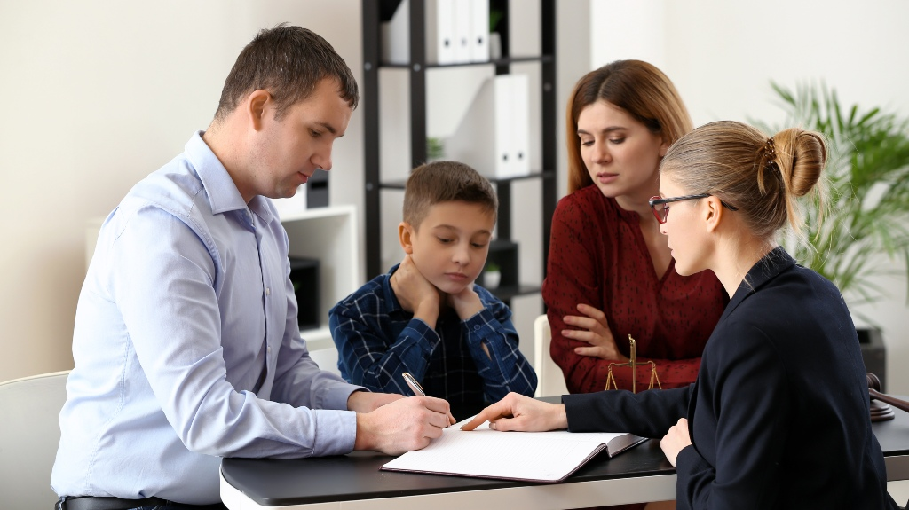 Four people, including a child, engaged in a formal discussion with documents at a table.